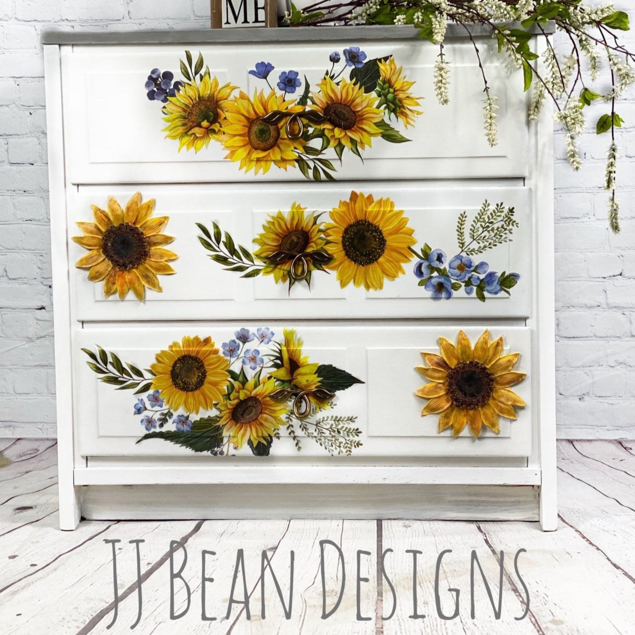 A 3-drawer dresser refurbished by JJ Bean Designs is painted white and features ReDesign with Prima's Sunflower Fields transfer on the drawers.