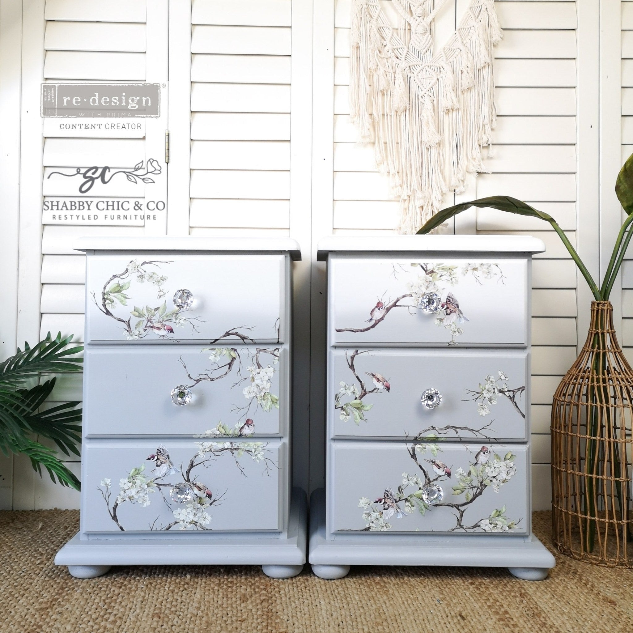 Two 3-drawer nightstands refurbished by Shabby Chic & Co. are painted an ombre blend of white down to light grey and feature ReDesign with Prima's Blossom Flight transfer on the drawers.