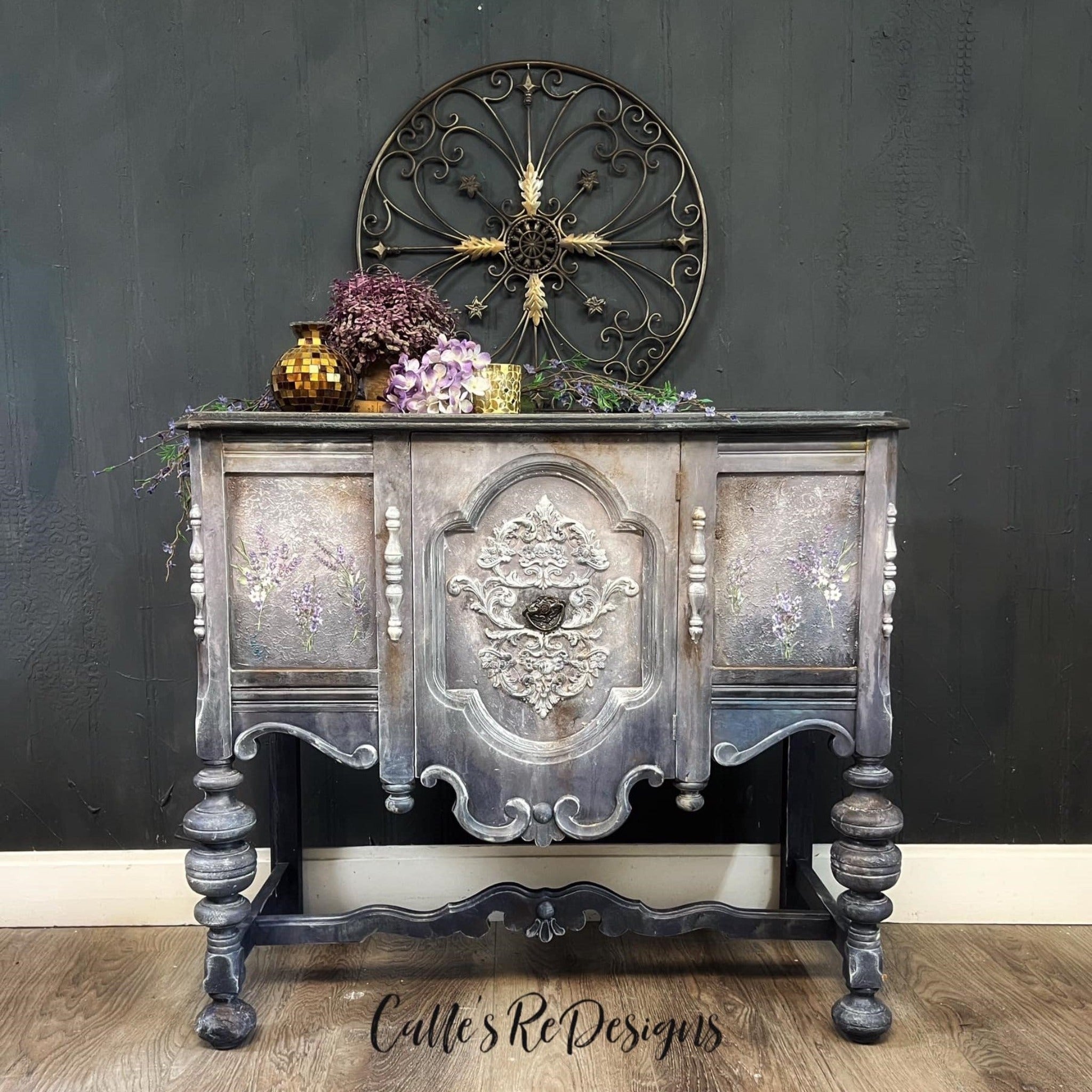 A small buffet table refubished by Calle's ReDesigns is painted an ombre blend of light grey down to dark grey and features ReDesign with Prima's Lavender Bunch small transfer on its 2 doors.