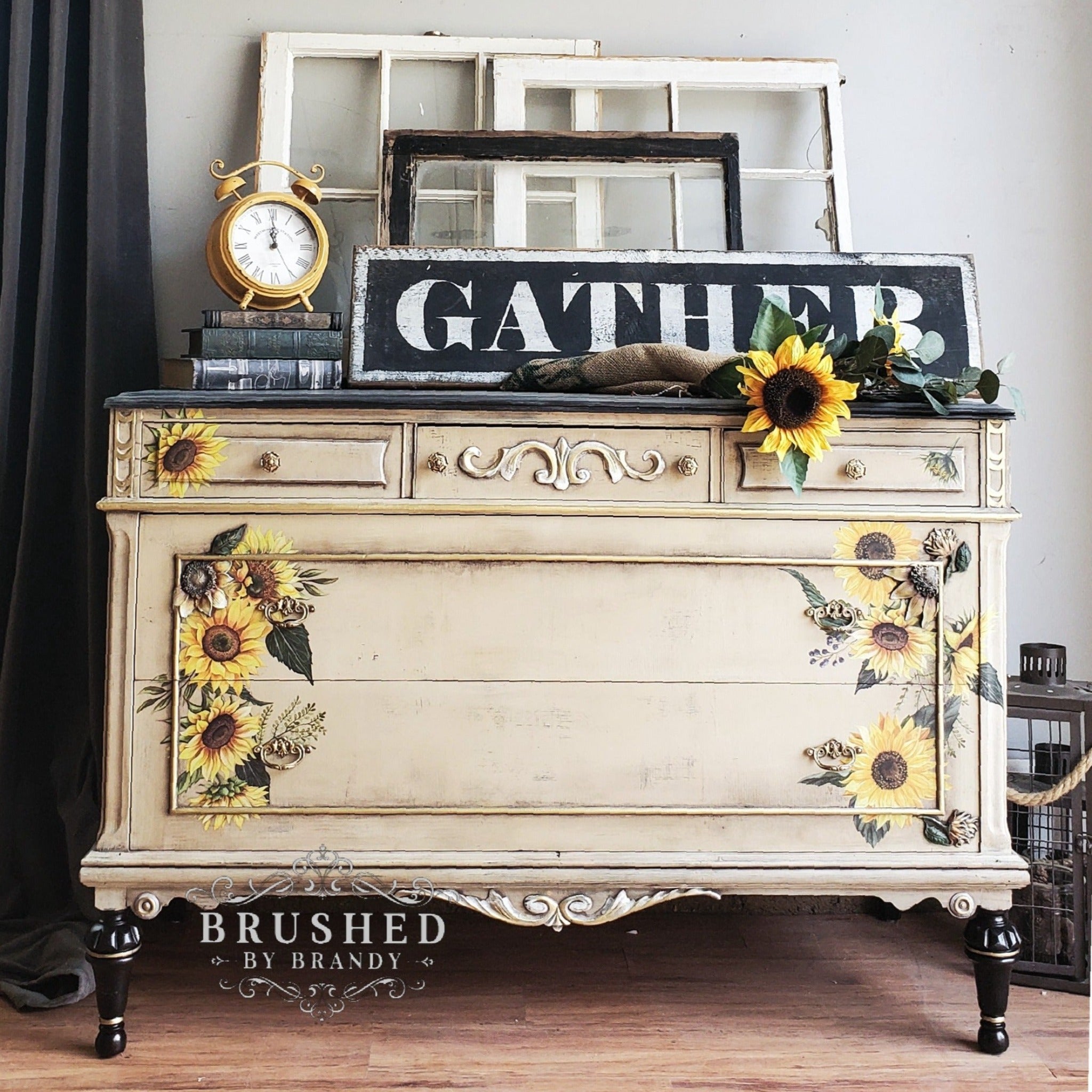 A vintage dresser refurbished by Brushed by Brandy is painted light tan and features ReDesign with Prima's Sunflower Fields on the front left and right sides of the drawers.