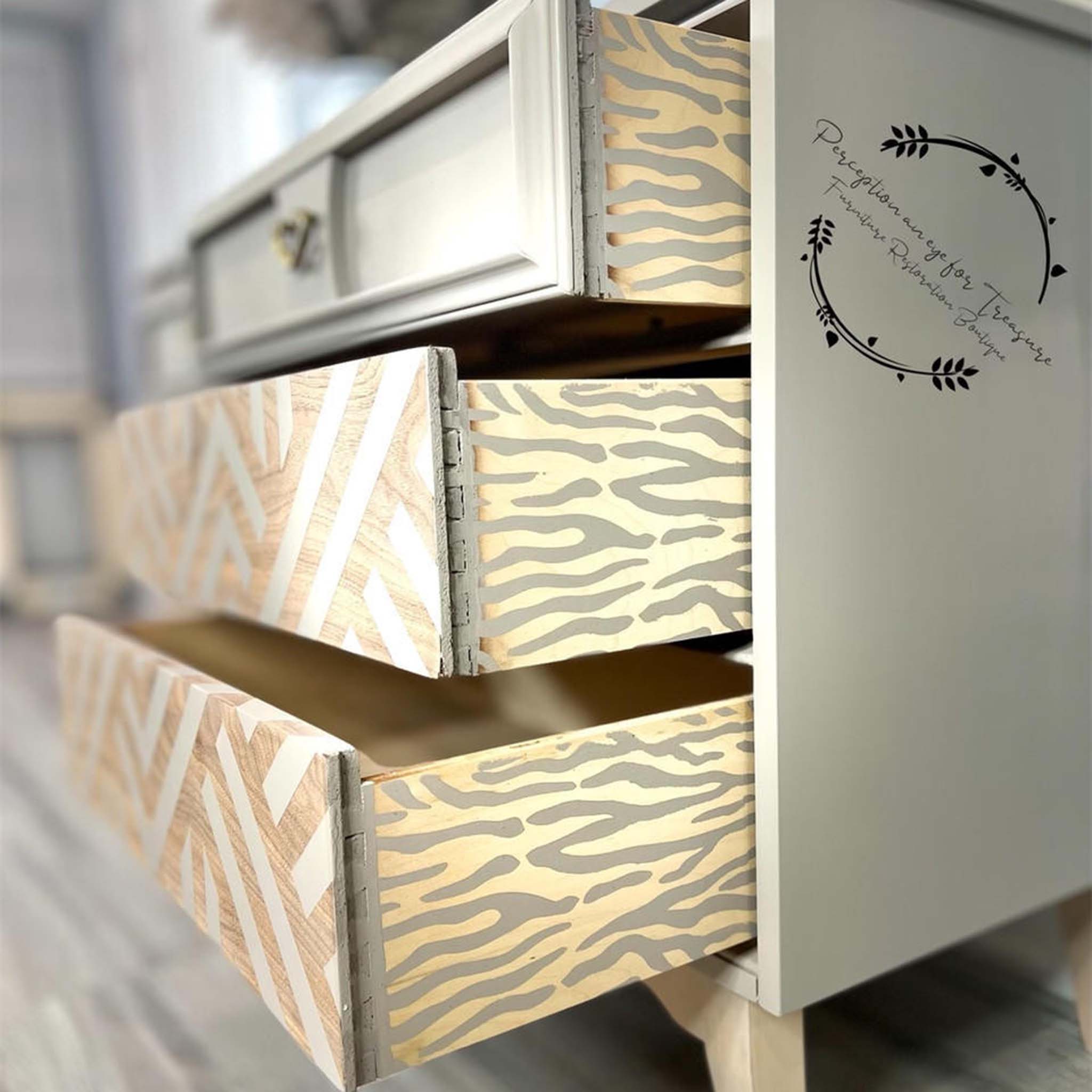A dresser refurbished by Perception an eye for Treasure Furniture Restoration Boutique is painted beige and features Belles & Whistles Safari mylar stencil in beige against natural light wood on the sides of the drawers.
