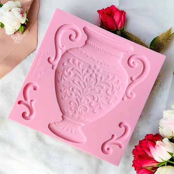Pink silicone mold with decorative design on a white surface with flowers.