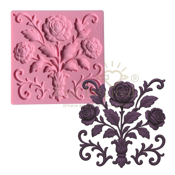 Pink silicone mold with floral design and purple decorative castings with roses on a white background