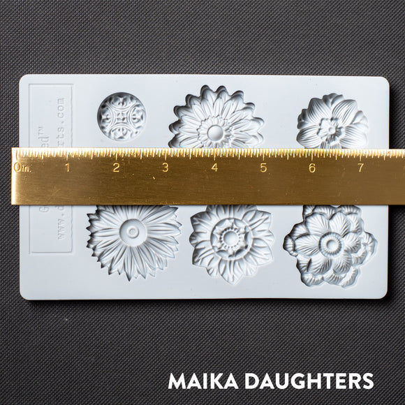 A light grey silicone mold featuring 6 posy flower heads is against a dark grey material background. A gold ruler reading 7.5" length sits on the mold.