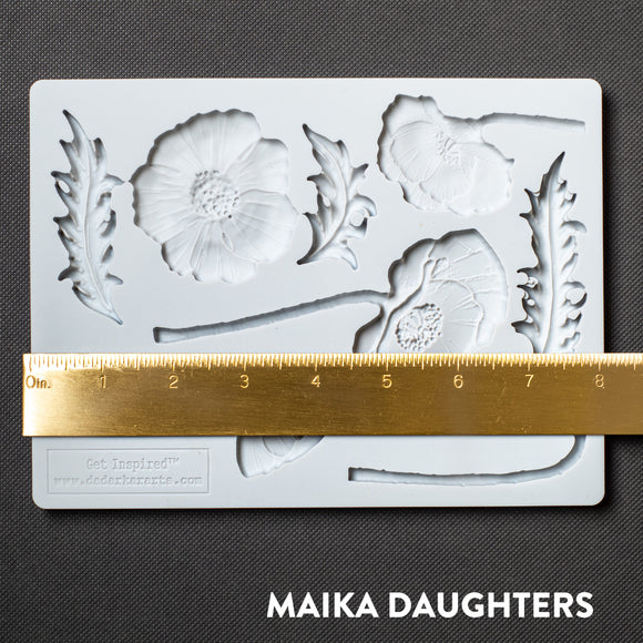 A light grey silicone mold featuring flower blooms, buds, and leaves is against a dark grey background. A gold ruler reading 8 inches width sits on the mold.