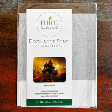 A package of Mint by Michelle's Haunted House 2 A3 decoupage paper is against a dark wood background.