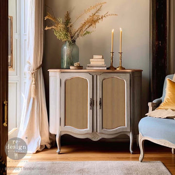 A vintage small buffet cabinet is painted a light brown-grey and features ReDesign with Prima's Timberlines A1 fiber paper on its 2 door inlays.