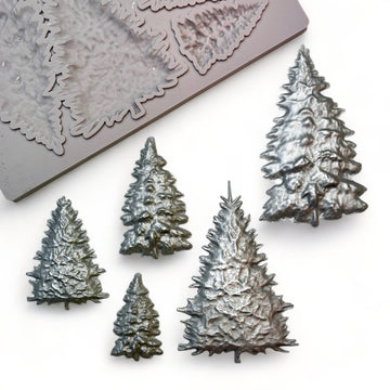 A beige silicone mold and silver colored castings of 5 varying size pine Christmas trees are against a white background.