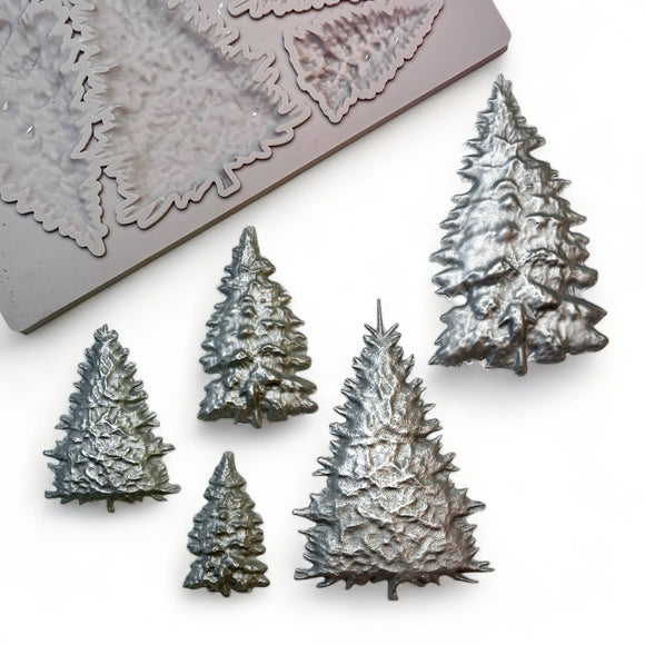 A beige silicone mold and silver colored castings of 5 varying size pine Christmas trees are against a white background.