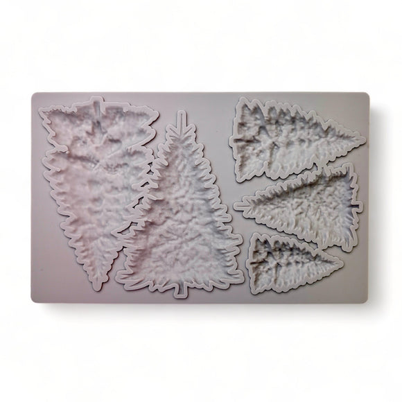 A beige silicone mold of 5 varying size pine Christmas trees is against a white background.