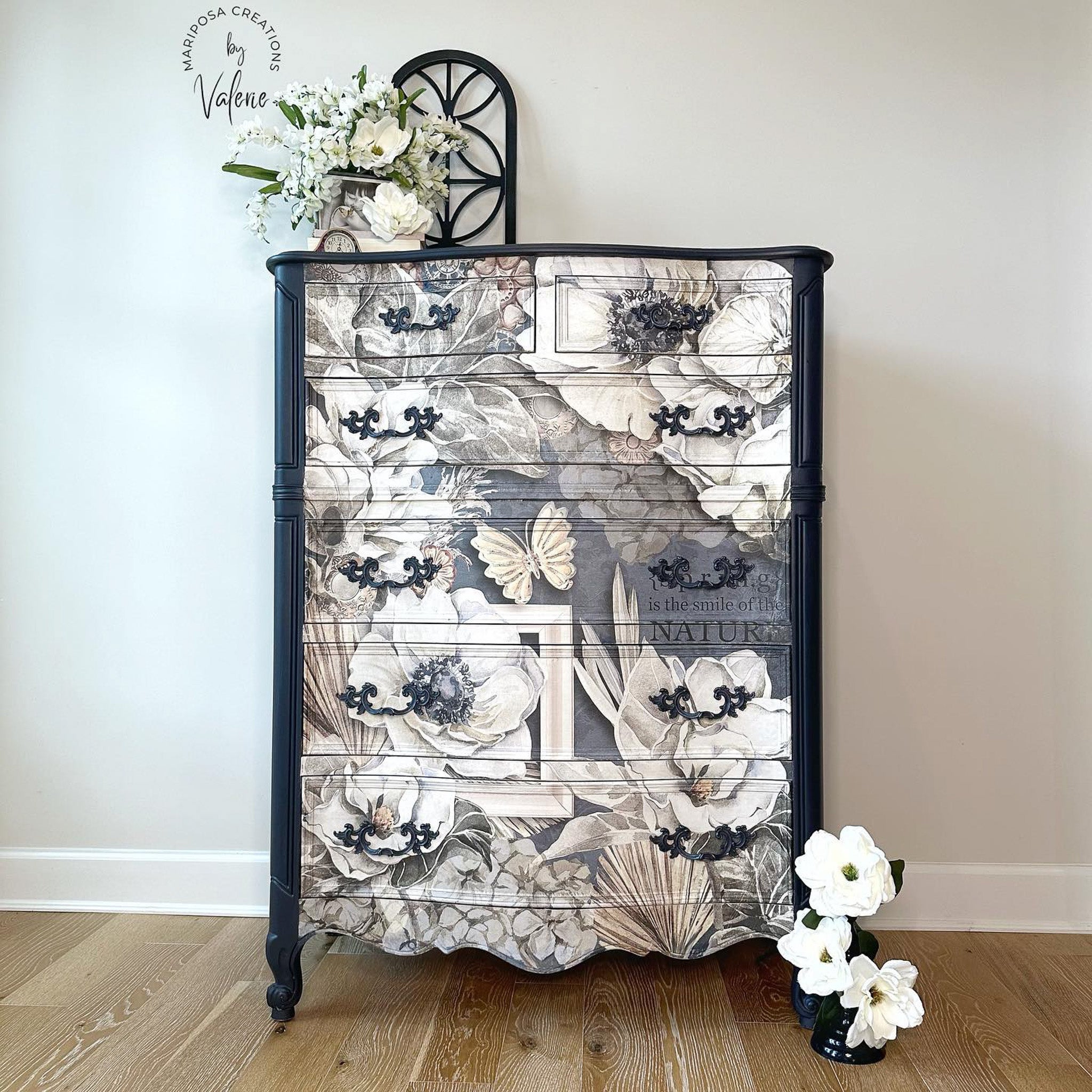 A vintage chest dresser refurbished by Mariposa Creations by Valerie is painted navy blue and features Decoupage Queen's Sugar Magnolia A0 rice paper on the whole front side.