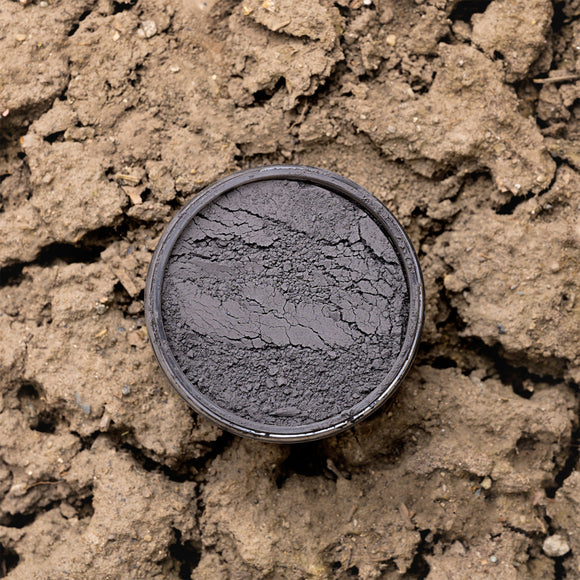 Black Dixie Dirt in a container on a textured brown surface