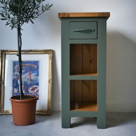 A small end table with 1 drawer and 2 cubby hold shelves is painted in Dixie Belle's Acadia Silk Paint and has natural wood accents.