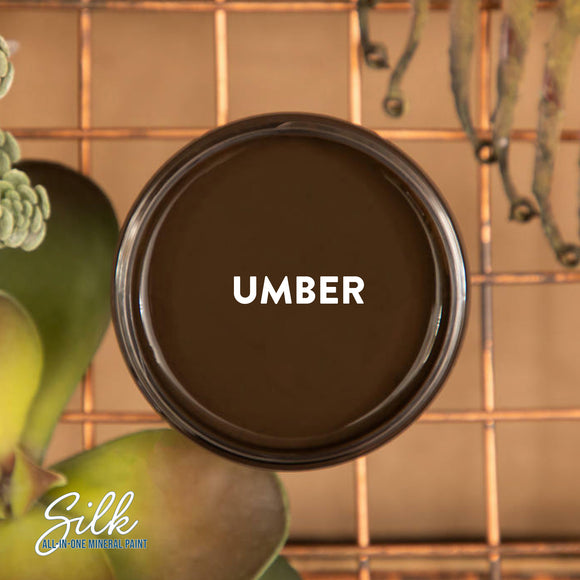An arial view of an open container of Dixie Belle Paint Company's Umber Silk All-In-One Mineral Paint is shown with white text reading Umber.