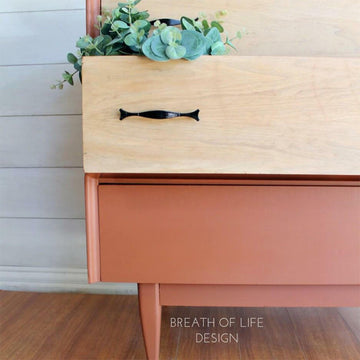 A close-up of a vintage night stand refurbished by Breath of Life Design has 2 natural wood drawers and features Dixie Belle Paint's Rusty Nail Chalk Mineral Paint on the rest of the unit.