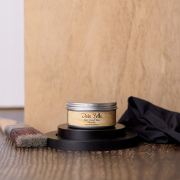 Jar of Dixie Belle wood finish on a wooden surface with a brush and cloth.