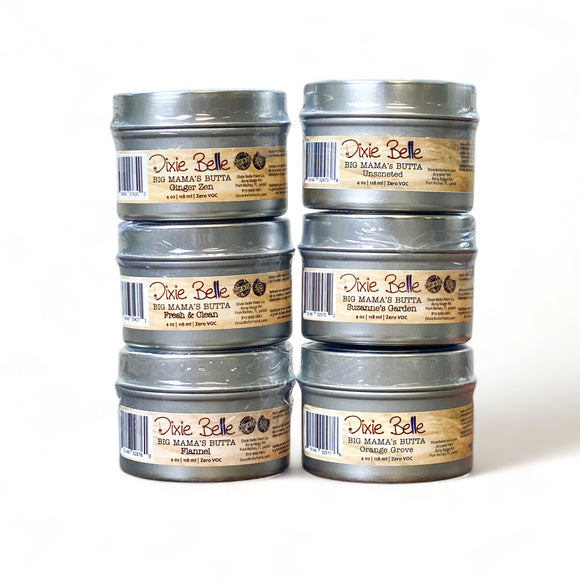 Two stacks of six 4 ounce tins of Dixie Belle's Big Mama's Butta in scents of Ginger Zen, Unscented, Fresh & Clean, Suzanna's Garden, Flannel, and Orange Grove are against a white background.