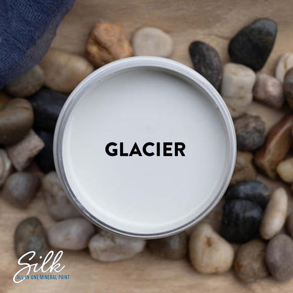 An arial view of an open container of Dixie Belle Paint Company's Glacier Silk All-In-One Mineral Paint is shown with black text reading Glacier.