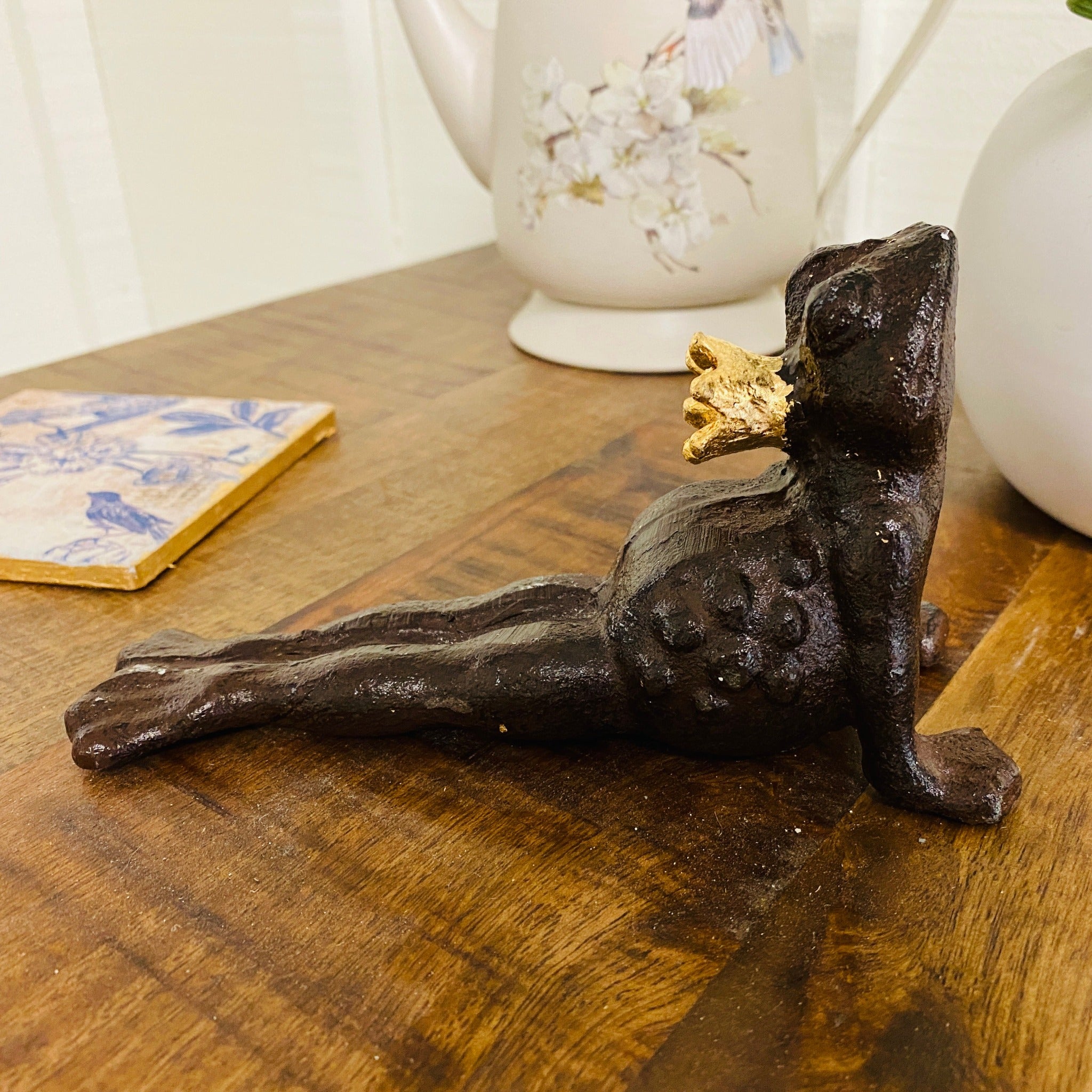 A ceramic frog in an upward facing dog yoga position is painted dark brown and features ReDesign with Prima's Kacha's Imitation Gold Leaf Foil on a crown on its head.