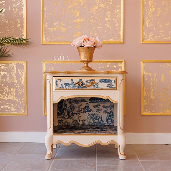A vintage nightstand with 1 drawer and an open cubby shelf refurbished by Kacha features Kacha Furniture paint in the color Creme Brulee (neutral beige) and has gold accents with a blue toile rub-on transfer.