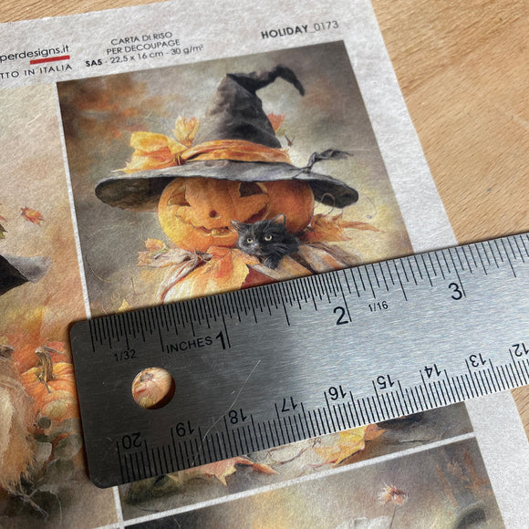Halloween-themed paper cutout with a pumpkin and witch hat on a wooden surface with a ruler for scale.