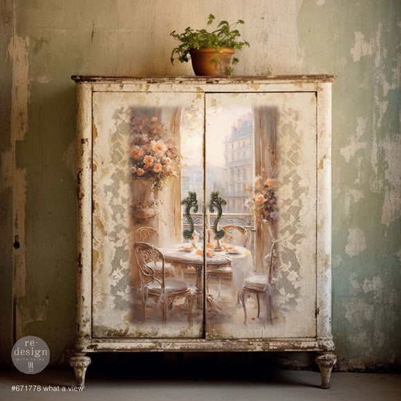 A vintage storage cabinet has weathered white paint and features ReDesign with Prima's What a View tissue paper on its 2 doors.