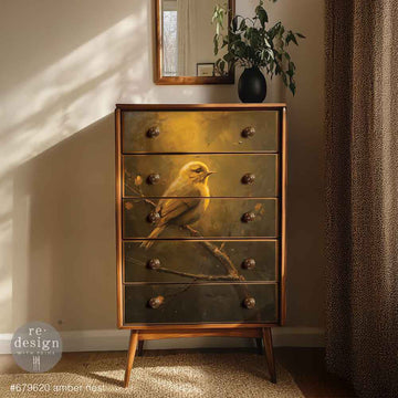 Wooden dresser with bird design on drawers in a room with sunlight and plant.