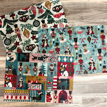 Three sheets of A3 fiber papers that feature vintage Christmas designs of nutcrackers and ornaments area against a light wood background.