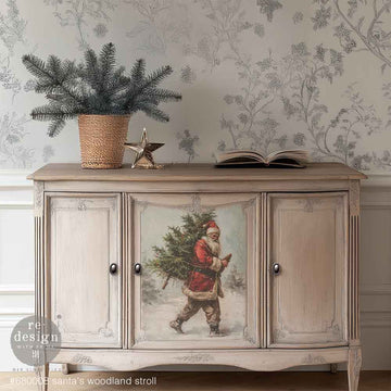 A vintage buffet cabinet is natural wood with white wash paint and features 1 design of Santa from ReDesign with Prima's Santas Woodland Stroll A3 fiber paper in the center door.