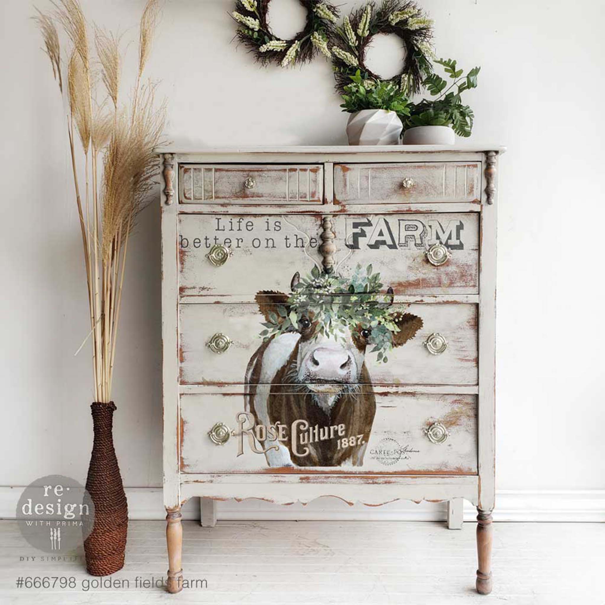 A vintage 5-drawer dresser is painted distressed grey and features ReDesign with Prima's Golden Fields Farm rub-on transfer on the bottom 4 drawers.