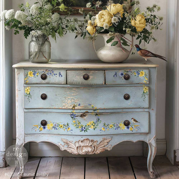 A vintage 5-drawer dresser is painted pale blue and features ReDesign with Prima's Sunlit Aviary small rub-on transfers on the drawers.