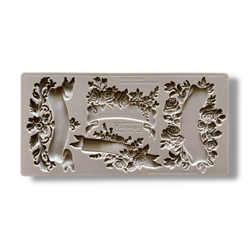 A silicone mold featuring 4 unique banners surrounded by delicate flowers is against a white background.