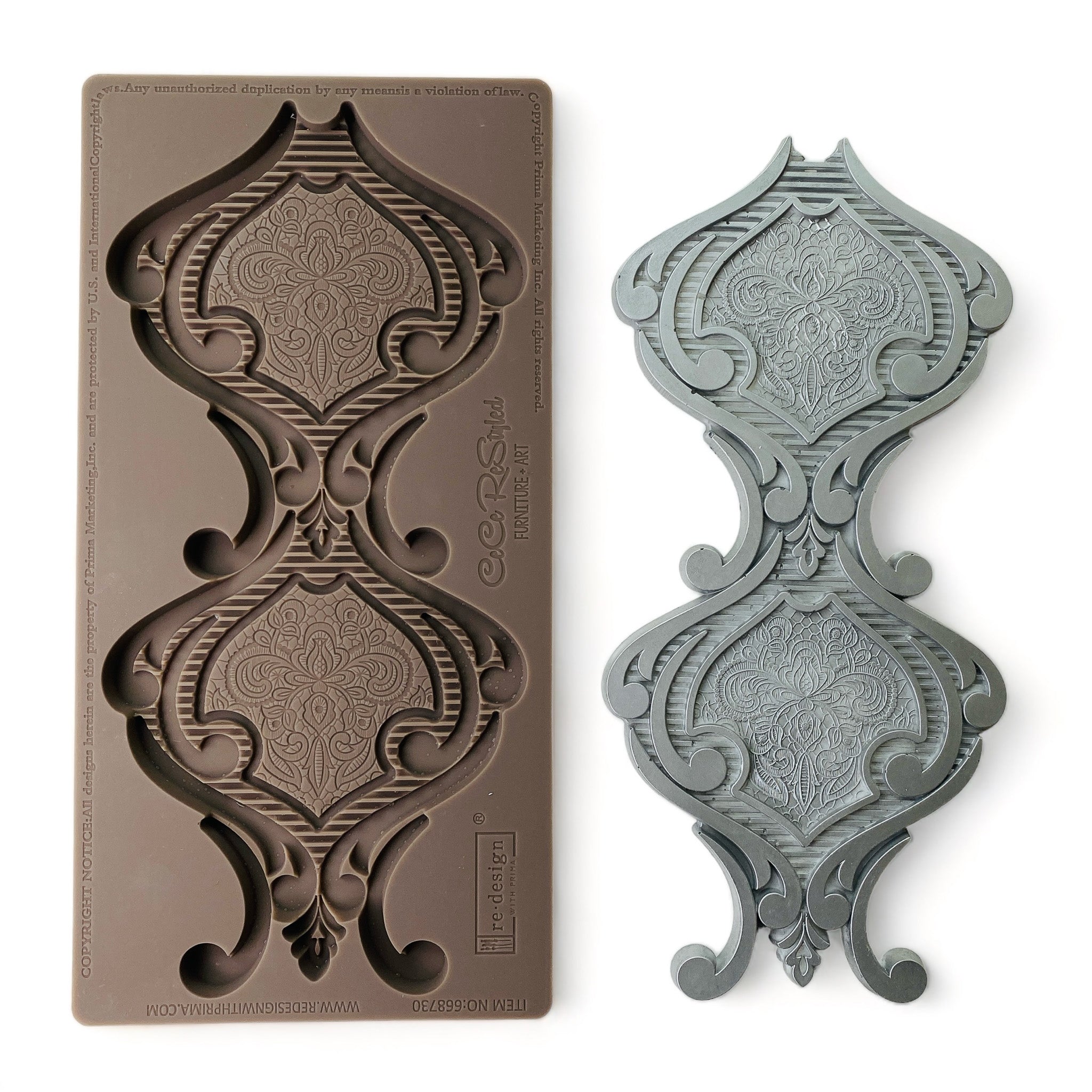A brown silicone mold and silver-colored casting that features a large hourglass shaped medallion are against a white background.