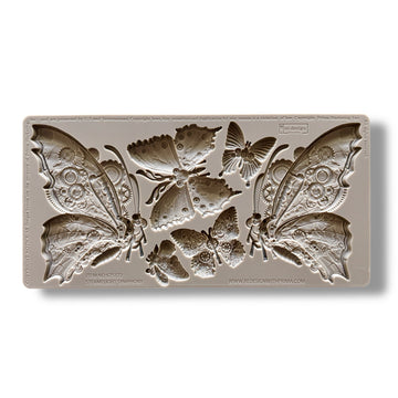 A silicone mold featuring 6 intricate butterflies, each embellished with cogs and gears is against a white background.