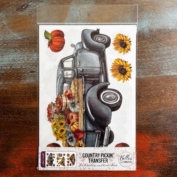 A package of Belles & Whistles' Country Pickin' rub-on transfer is against a dark wood background.