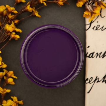 An arial view of an open container of Dixie Belle Paint Company's Amethyst Chalk Mineral Paint. Yellow flowers surround the left side of the paint.