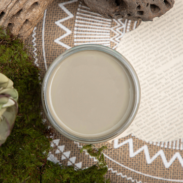 An arial view of an open container of Dixie Belle Paint Company’s Spanish Moss Chalk Mineral Paint is surrounded by green peat moss and driftwood.