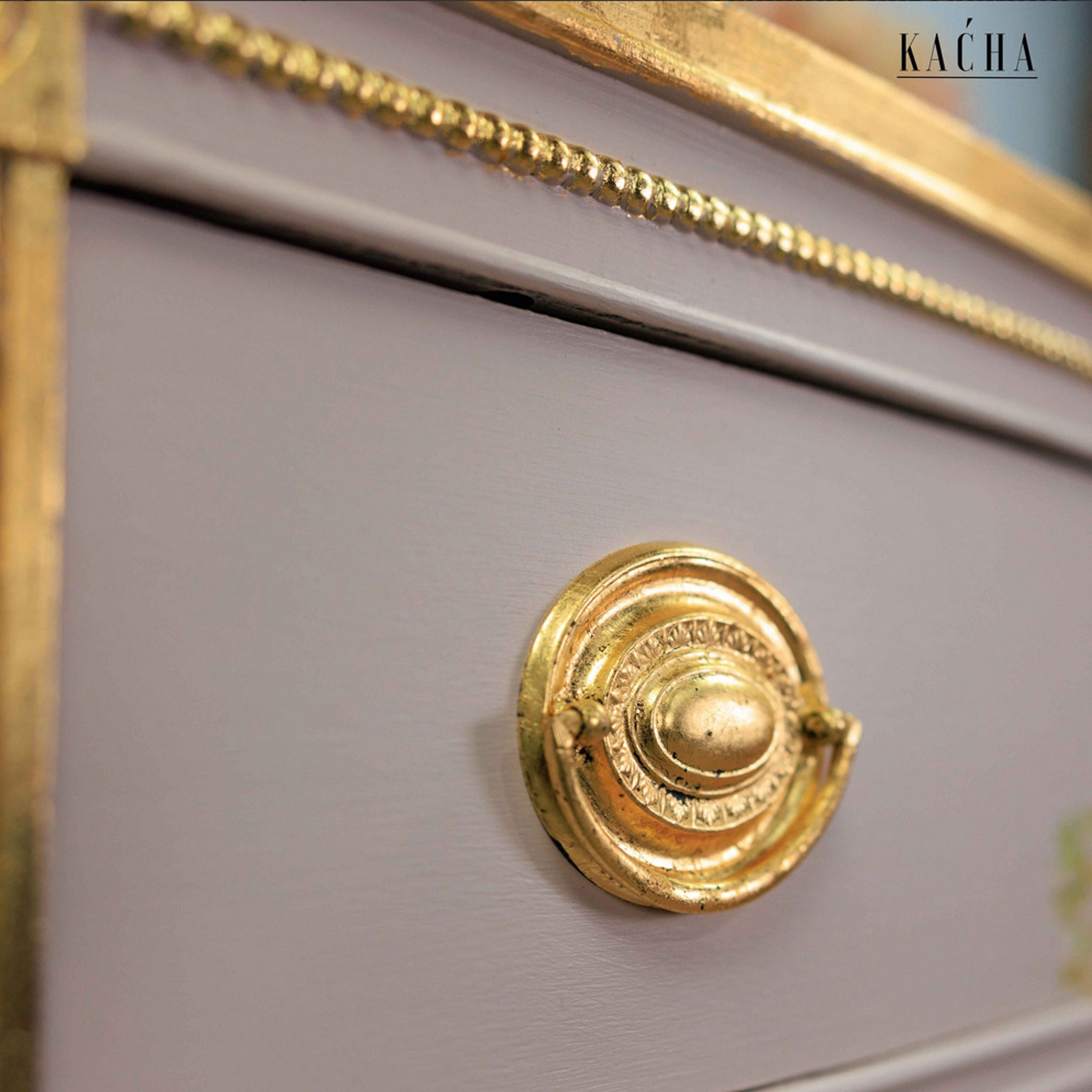A close-up view of a vintage dresser refurbished by Kacha is painted a soft rose pink and features the Imitation Gold Leaf Foil on the trims and knobs.