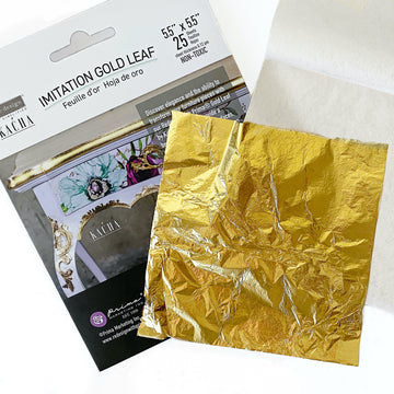 Flat 5.5" by 5.5" package of Redesign with Prima's by Kacha 25 sheets of Imitation Gold Leaf. A sample of one full sheet of gold foil sits on the package.