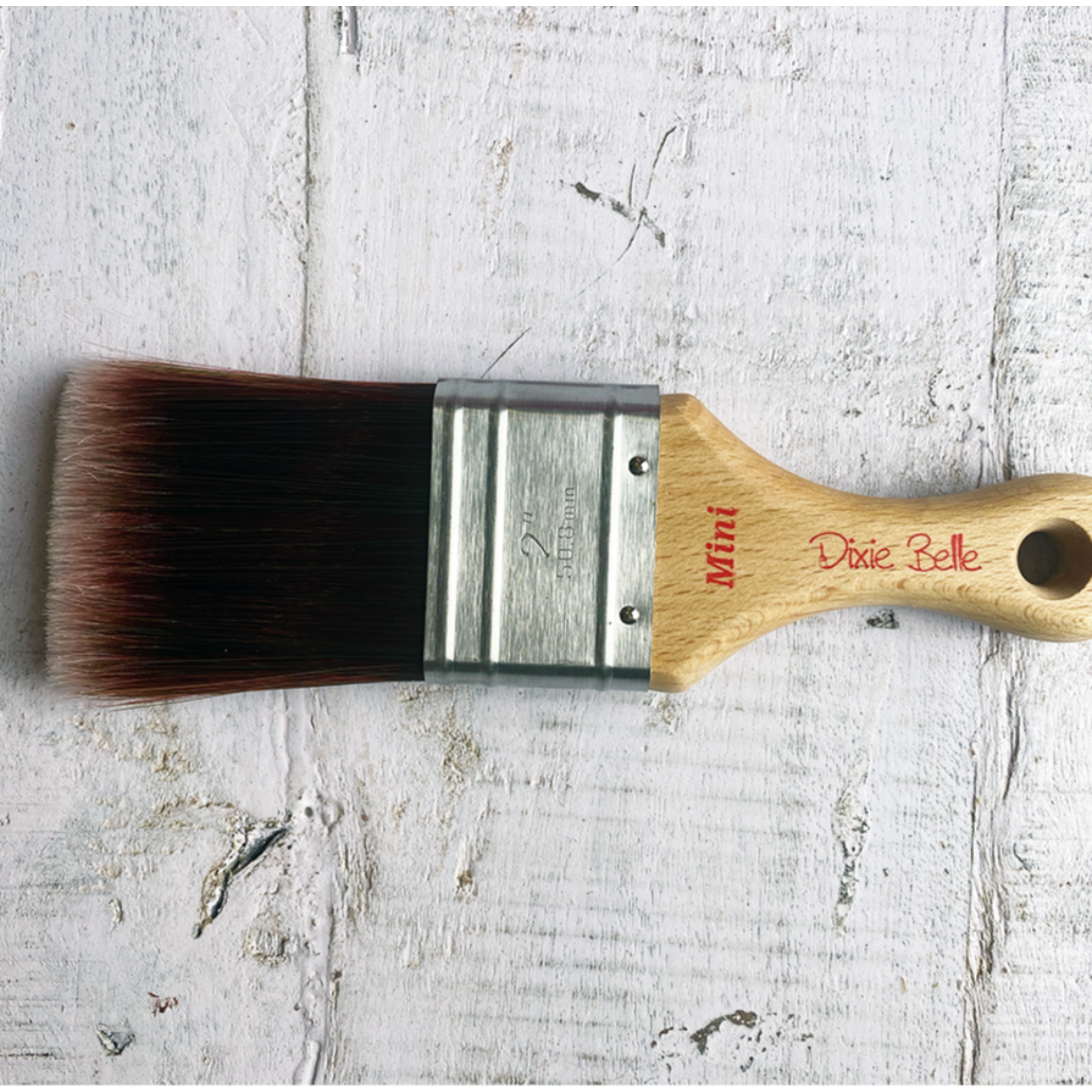 Dixie Belle Paint Company's Mini Synthetic Paint Brush is against a white wood background.