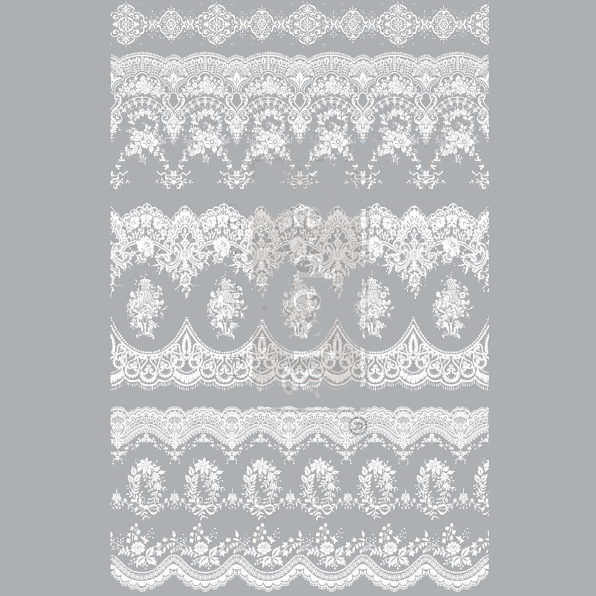 Small rub-on transfer of a white vintage lace wallpaper design on a grey background. Grey borders are on the sides.