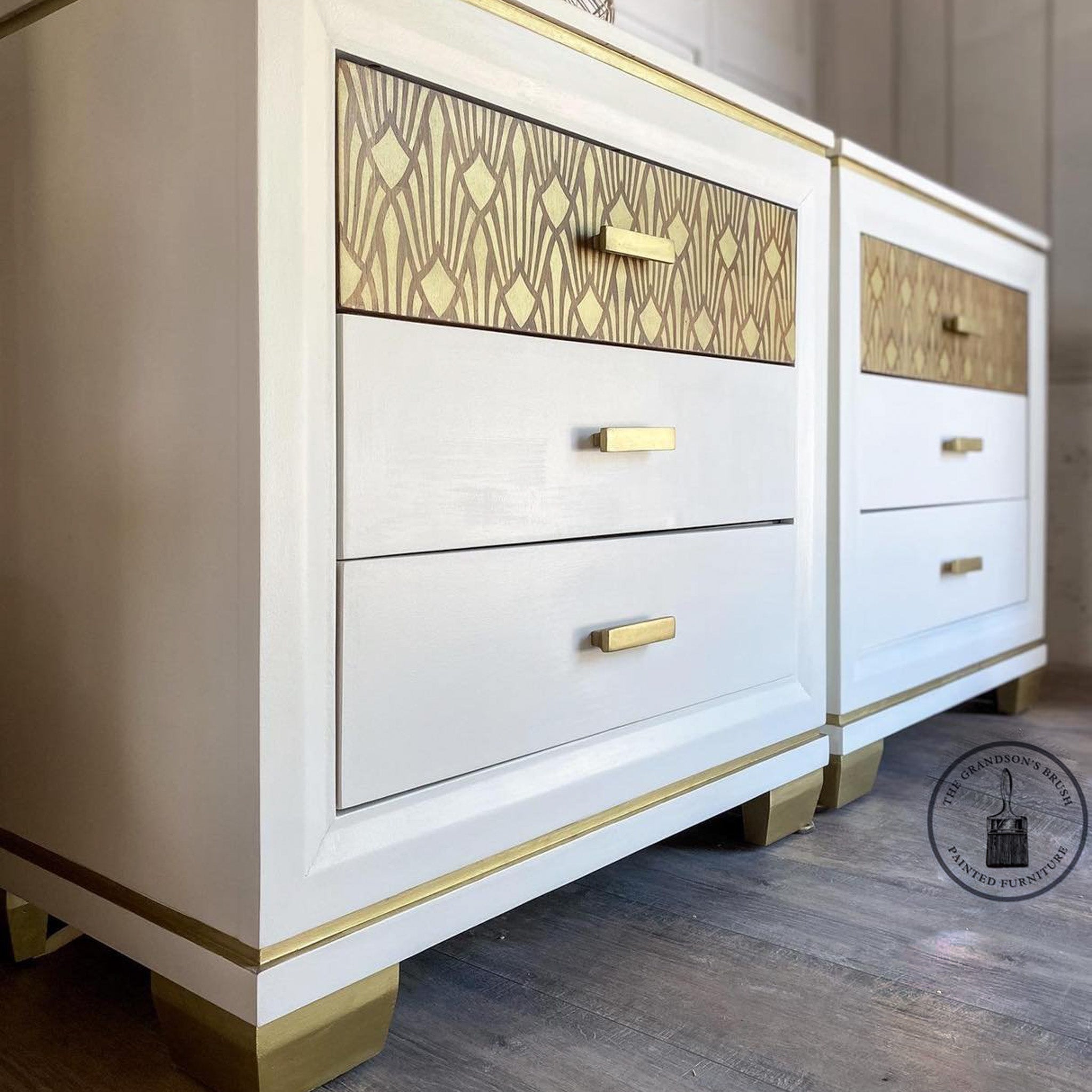 Close-up of 2 white with gold accented nightstands refurbished by The Grandson's Brush feature ReDesign with Prima's Sunlit Diamonds stencil in gold over brown.