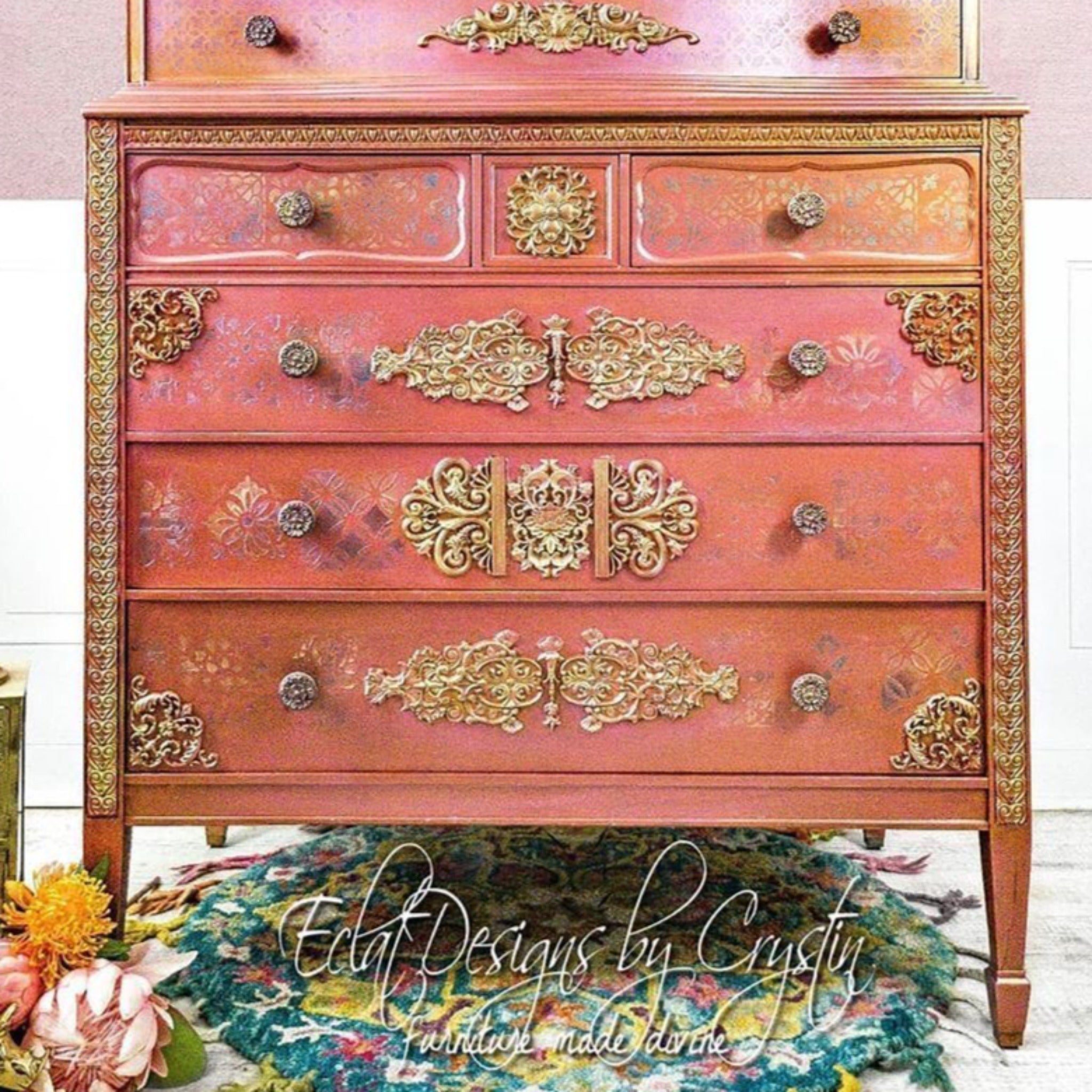 A vintage chest dresser refurbished by Eclat Designs by Crystin is painted coral pink with gold accents and features ReDesign with Prima's Golden Emblem silicone mould on its drawers.