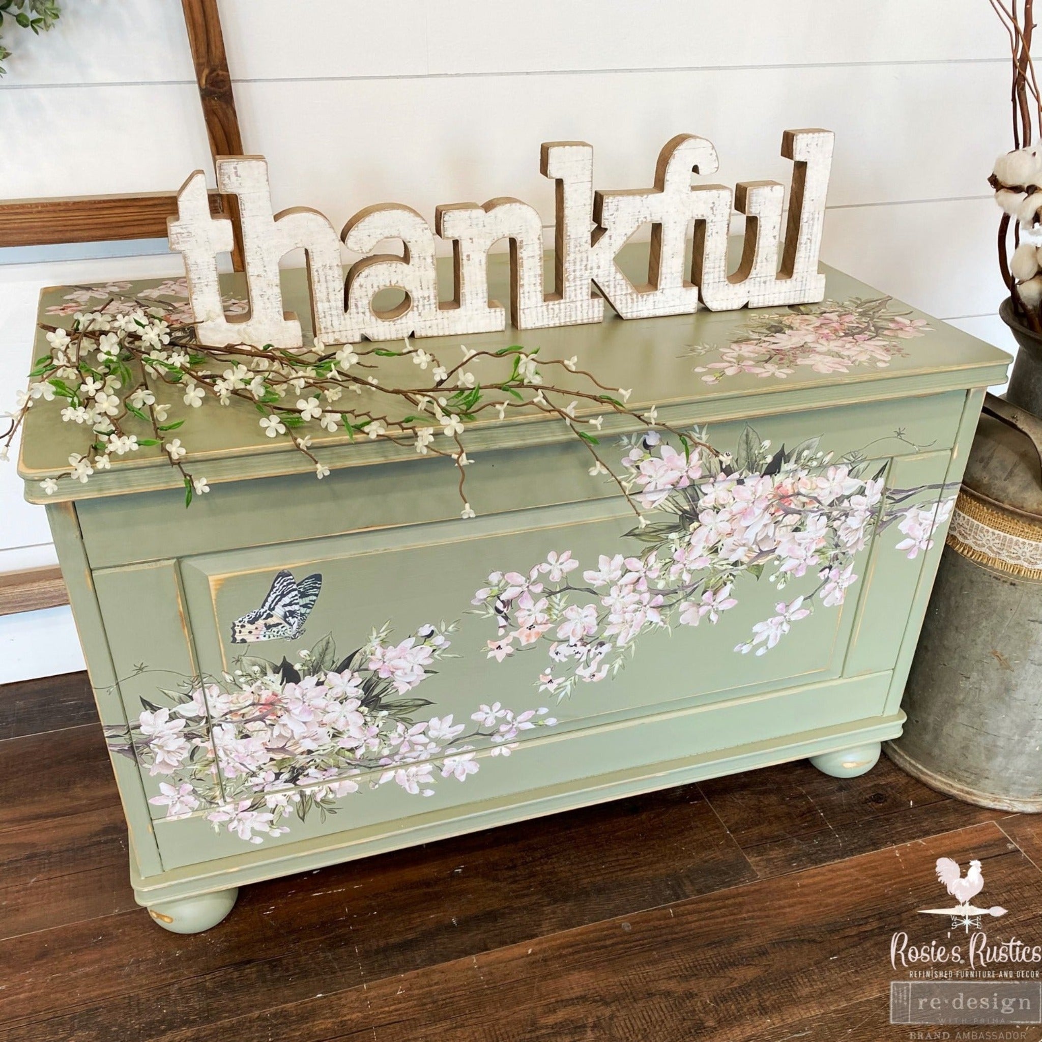 A storage chest refurbished by Rosie's Rustics is painted light green and features ReDesign with Prima's Blossom Botanica on it. A large wood cut-out that says "thankful" sits on the chest.