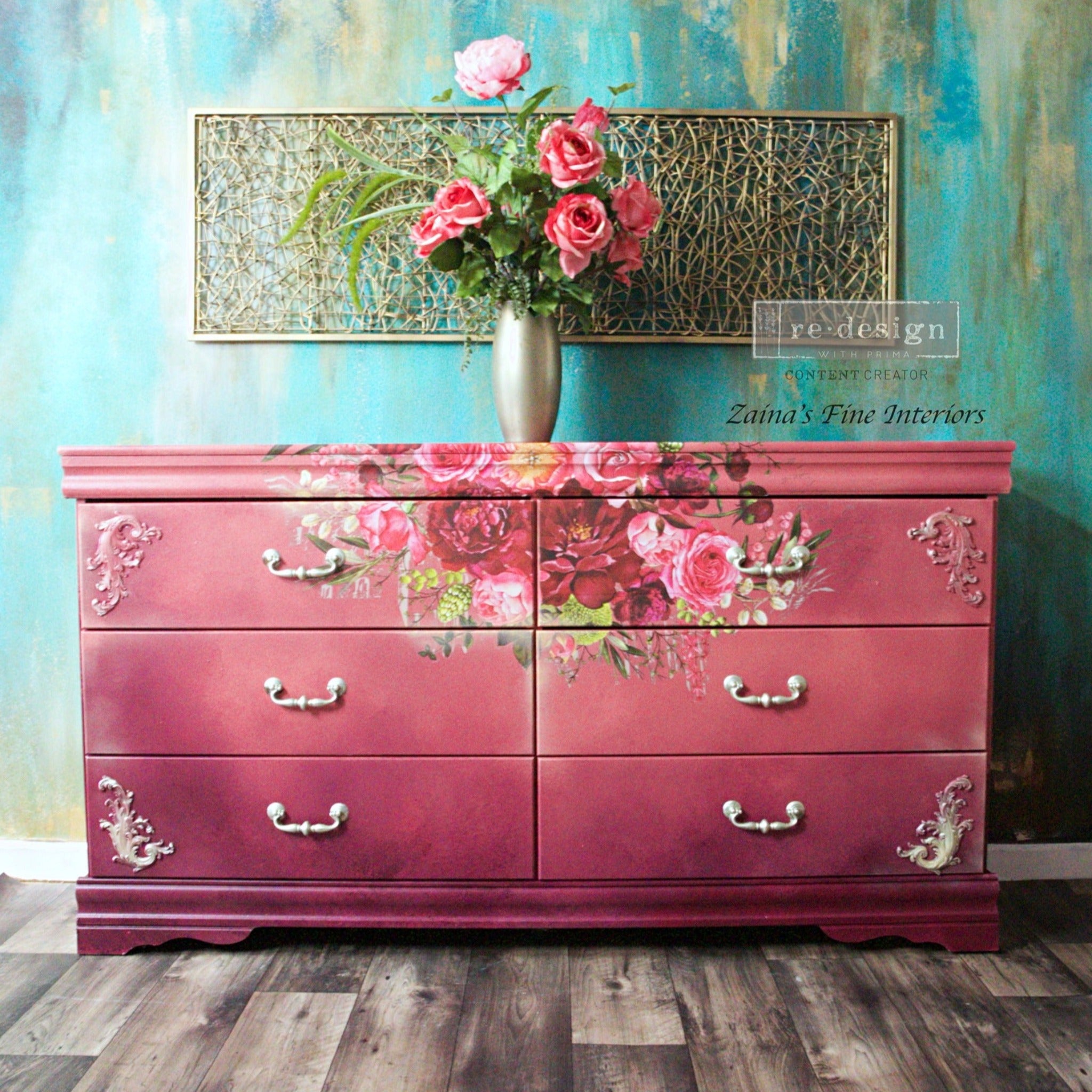A vintage 6 drawer dresser refurbished by Zaina's Fine Interiors is painted an ombre is coral pink down to maroon and features ReDesign with Prima's Royal Burgundy transfer at the top center of it.
