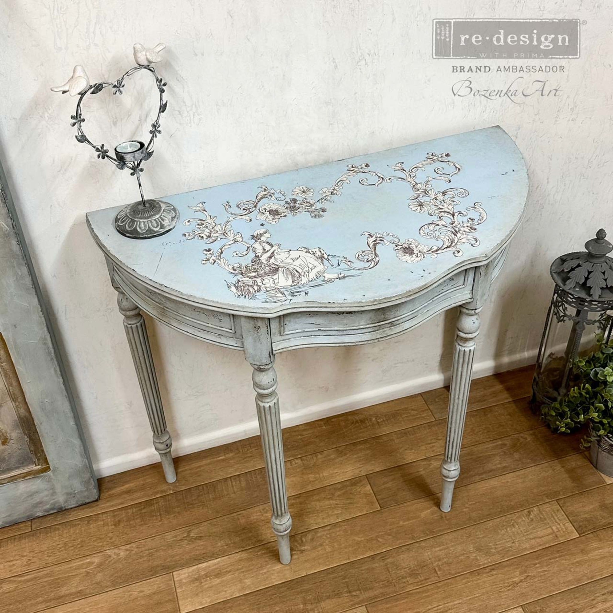 A vintage half-circle side table refurbished by Bozenka Art is painted pale blue and features ReDesign with Prima's Alaina Toile transfer on the top.