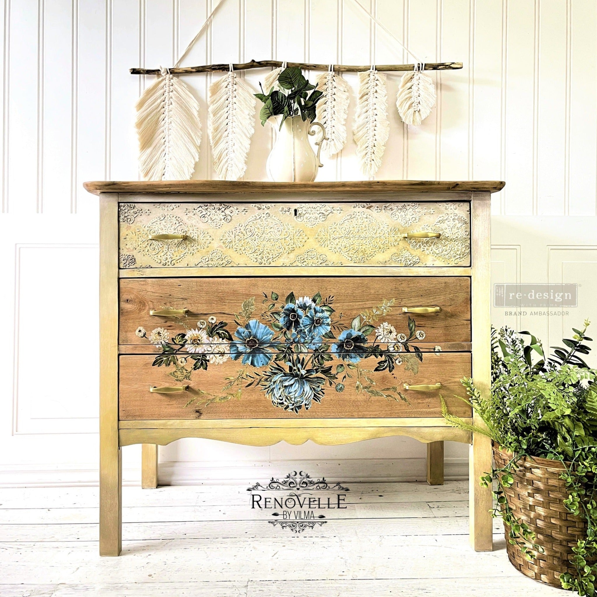 A 3-drawer dresser refurbished by Renovelle by Vilma is stained natural wood and features ReDesign with Prima's Gilded Floral small transfer in the enter of its bottom 2 drawers.