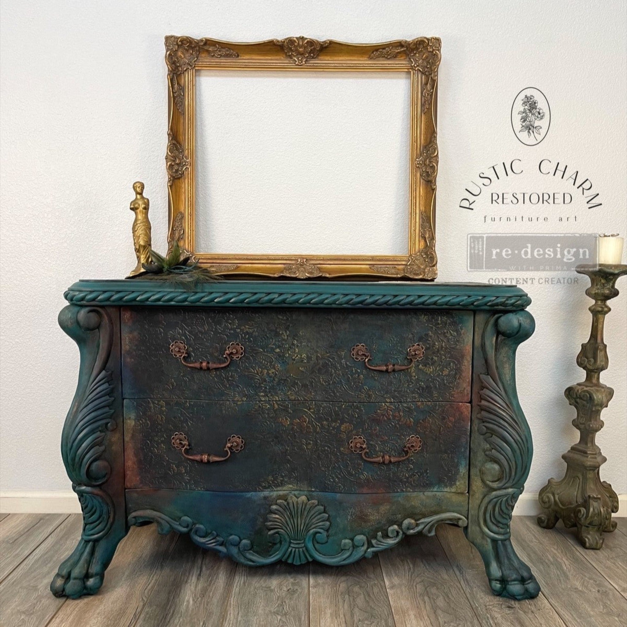 A vintage 2-drawer dresser refurbished by Rustic Charm Restored is painted a blend of dark teal, rust orange, and golden yellow and features ReDesign with Prima's Aged Patina A1 fiber paper on its drawers.