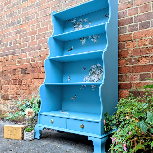 A vintage hutch top turned into a bookcase is painted sky blue and features ReDesign with Prima's Blossom Botanica on its backboard.