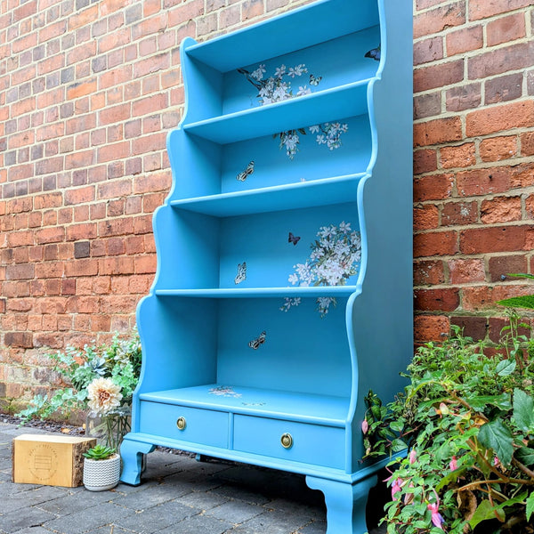 A vintage hutch top turned into a bookcase is painted sky blue and features ReDesign with Prima's Blossom Botanica on its backboard.